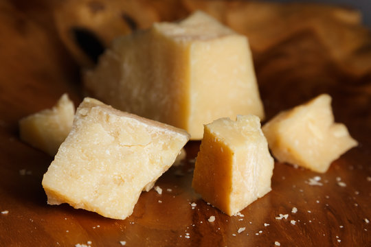 Parmesan cheese on a wooden board. Pieces of cheese close-up.