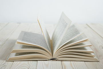 Open of pastel colorsbooks hardback on wooden table. Copy space. Selective focus. Knowledge concept