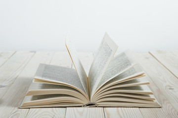 Open of pastel colorsbooks hardback on wooden table. Copy space. Selective focus. Knowledge concept