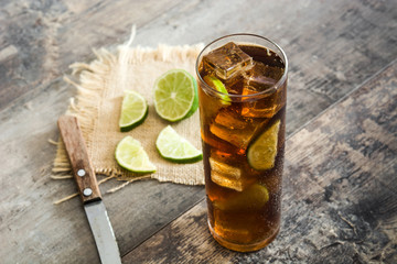 Cuba libre. Cocktail with rum, lime and ice on wooden table