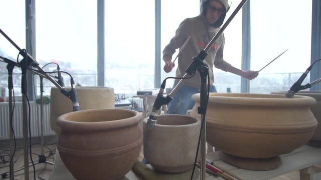 Slider shooting as a nosy drummer playing unusual music on clay pots