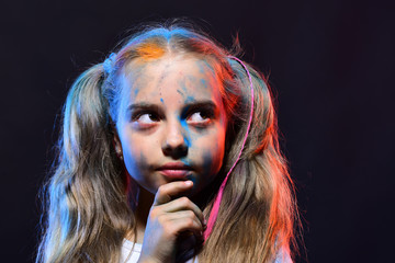 Fototapeta premium Schoolgirl has paint spots on face. Girl with thoughtful face
