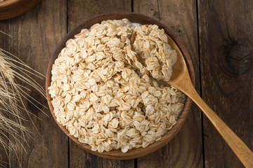 Rolled oats, oats in bowl and jug of milk on wooden background

