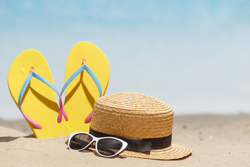 Flip flops, sunglasses and accessiores on sandy beach. holidays background. Copy space.