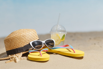 Flip flops, sunglasses and accessiores on sandy beach. holidays background. Copy space.