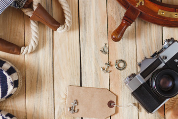 Striped slippers, camera, bag and maritime decorations on the wooden background