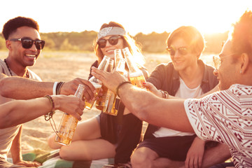 Young group of friends outdoors on the beach drinking beer.