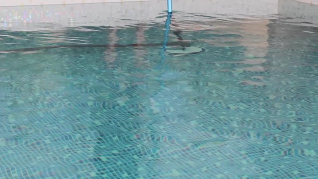cleaning the bottom of the pool with a special mop