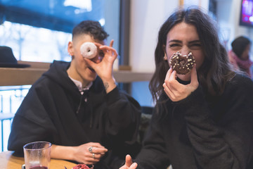  two women lesbian couple indoor playing doughnuts having fun - happiness, food and drink, snack concept