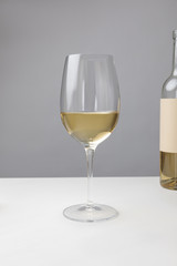 Closeup view of white wine glass and bottle on gray