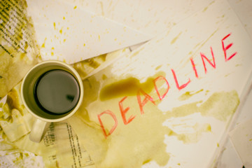 Deadline written on paper in red on the background of spilled coffee.