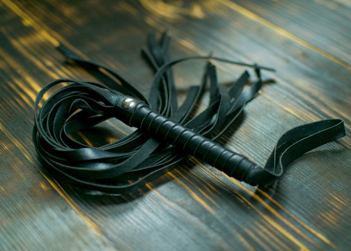 Whip for BDSM  on a dark background. Accessory for sexual games.