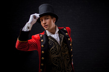 Showman. Young male entertainer, presenter or actor on stage. The guy in the red camisole and the cylinder.