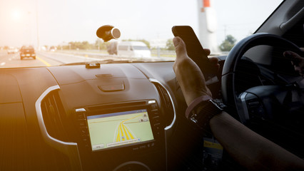 Man driving car with GPS map system in car while using mobile phone