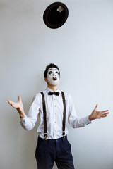 The clown mime throws the hat to the top. Throw a hat. Black hat. Clown mime.
