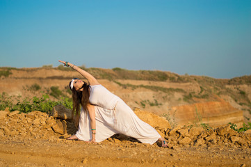 Girl in white clothes doing yoga in nature. Relaxation. Mountainous terrain.