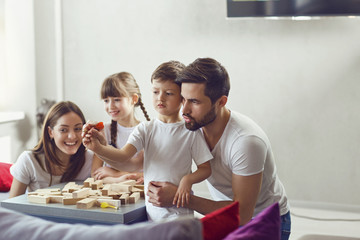 Happy family playing board games at home. Mother, father and children play together.