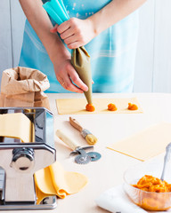 Obraz na płótnie Canvas Woman making ravioli pumpkin blue cheese pasta machine