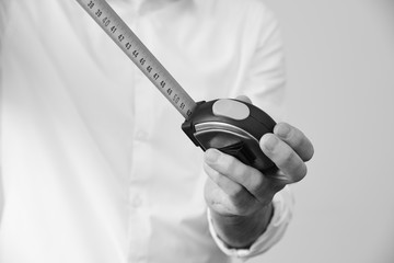 Businessman in a smart white shirt holds a measuring tape in his hand - metaphora for well planned concepts