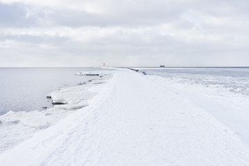 A pier to the lighthouse at the mouth in winter