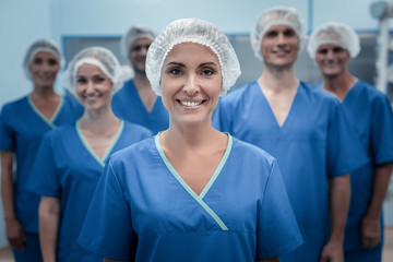 Medical team. Delighted nice female surgeon wearing uniform and standing in front of her team while...