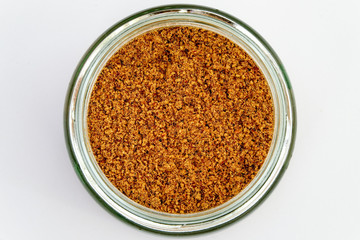 Rose hip powder in a glass jar. Close up with white background.