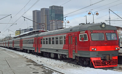 The electric train stands near the platform of the railway station