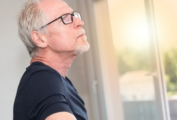 Portrait of pensive senior man, light effect