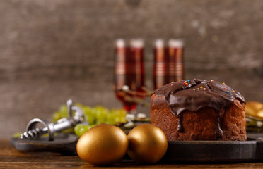 Delicious home-made Easter cake in chocolate glaze, vintage glasses with red wine and traditional painted eggs. A beautiful Easter still life with a place under your text.