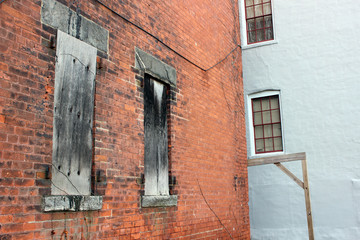 Fototapeta na wymiar Boarded up windows on abandoned industrial urban brick factory building 