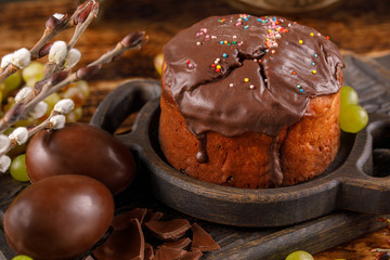 Delicious homemade Easter cake in chocolate glaze with chocolate eggs and grapes. Easter cake closeup.