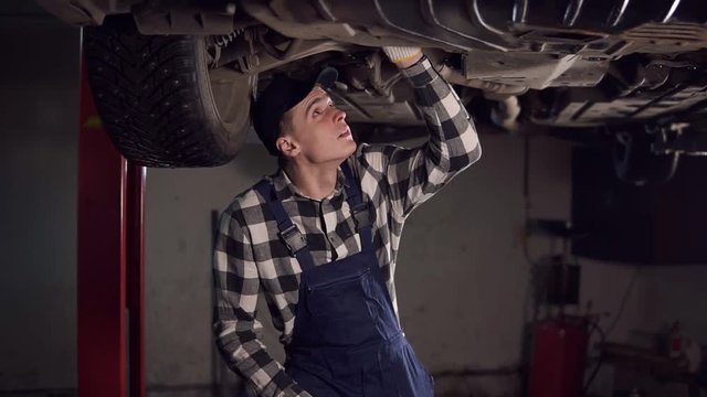Handsome mechanic reparing a car in his workshop.