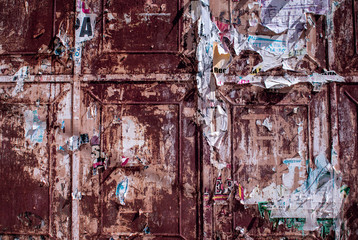 Rusty doors with old torn ads and posters, grunge vintage background