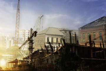 Double exposure building and tower crane under construction with sunset