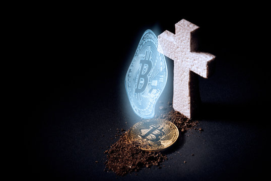white grave cross and bitcoin sprinkled with earth. The concept of the fall of the cost of bitcoin and its death as the most expensive crypto currency