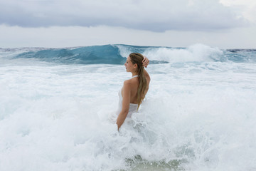 Young woman in a white shirt is bathed in the ocean