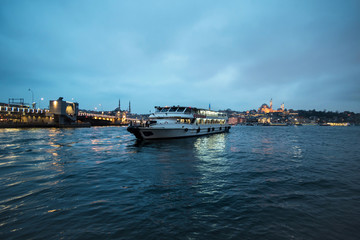 Fototapeta na wymiar Views of Galata bridge and a ferry in Klarios river at night, Istanbul Turkey