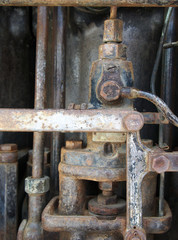 detail of the cylinder and pipes in an old rusted decaying abandoned big petrol engine with bolts pipes and rods