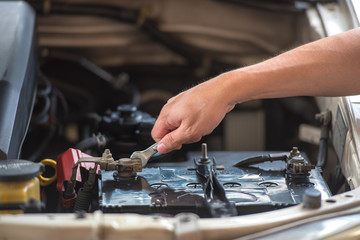 Action of man hands using spanner remove car battery terminals to change the new one, car fixing and maintenance service concept.