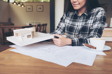 A woman architect working on an architecture model with shop drawing paper and coffee cup on table
