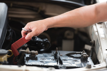 Action of man hands using spanner remove car battery terminals to change the new one, car fixing and maintenance service concept.