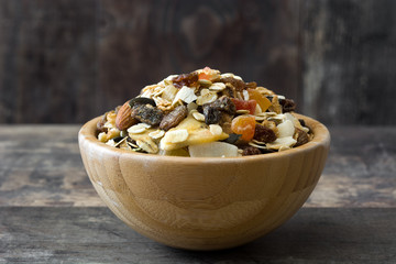 Muesli and dried fruit in wooden bowl on wooden table. 