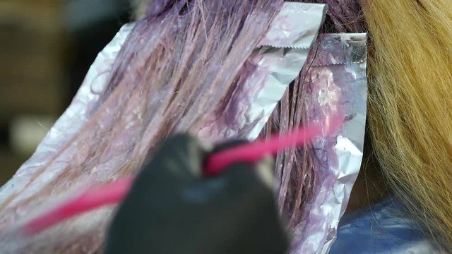 hairdresser makes hairstyle, dye for a teenager in a beauty salon. Hair covered in dye. 4K