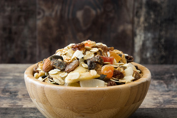 Muesli and dried fruit in wooden bowl on wooden table. 