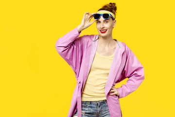 Young woman on a yellow background and pink coat and sunglasses. Colour obsession concept.  Minimalistic style. Stylish Trendy