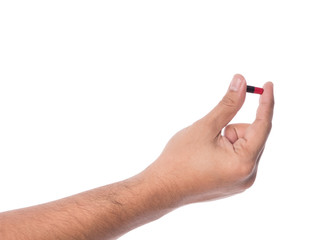 Hand holding a capsule or pill isolated on white.