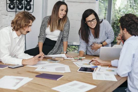 Young pregnant woman at work with his associates in the office during a meeting