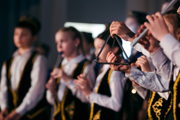  Little girl hands is playing on a musical triangle at stage close-up. Children orchestra in Tatar...