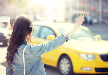 gesture, transportation, travel, tourism and people concept - young woman or teenage girl catching taxi on city street or hitch-hiking