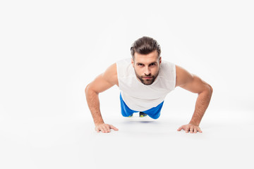 Front view  portrait of concentrated, confident, sporty, athletic, attractive  man making, showing push up position, isolated on white background